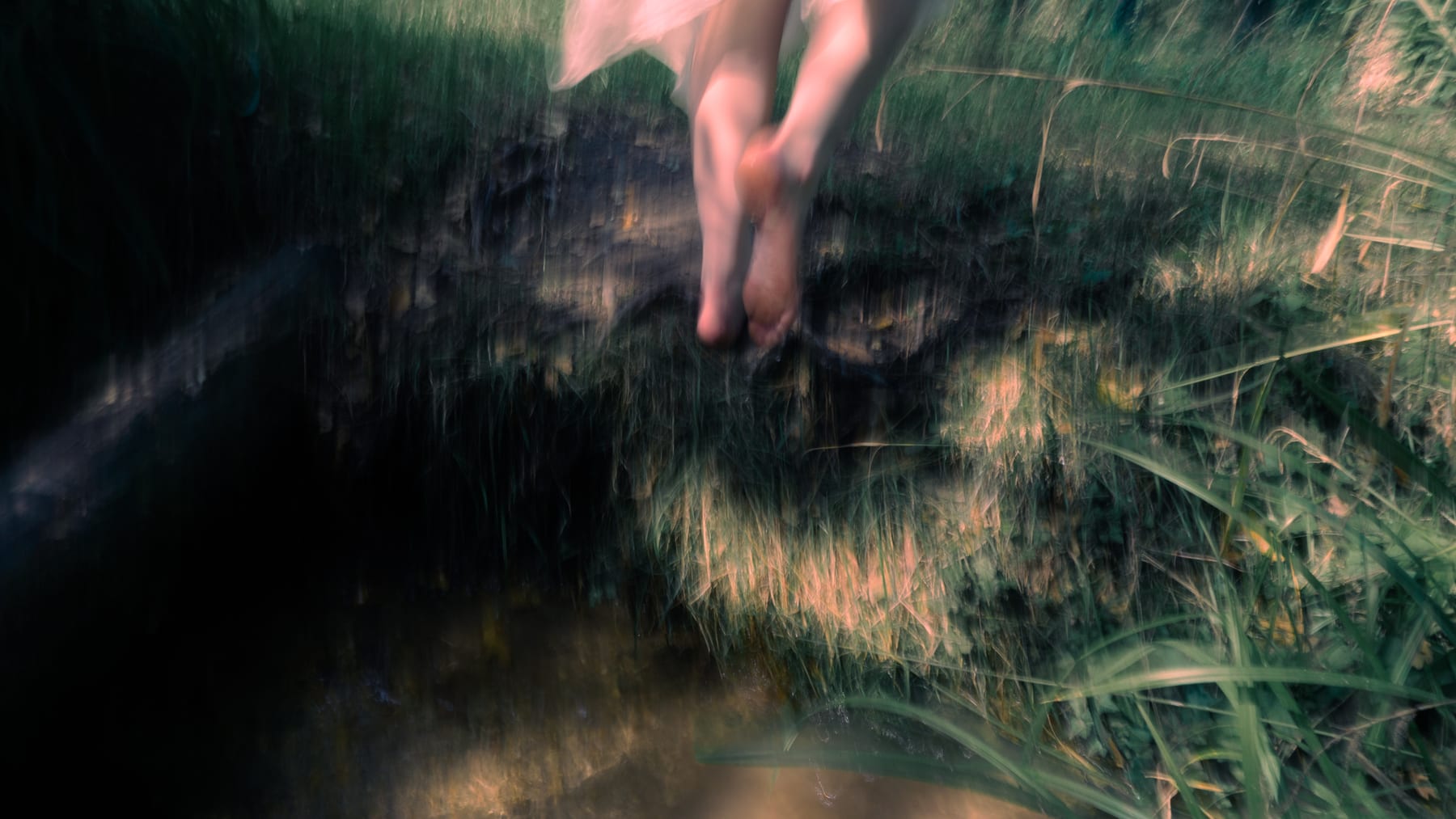 Motion-blurred bare feet in long grass.