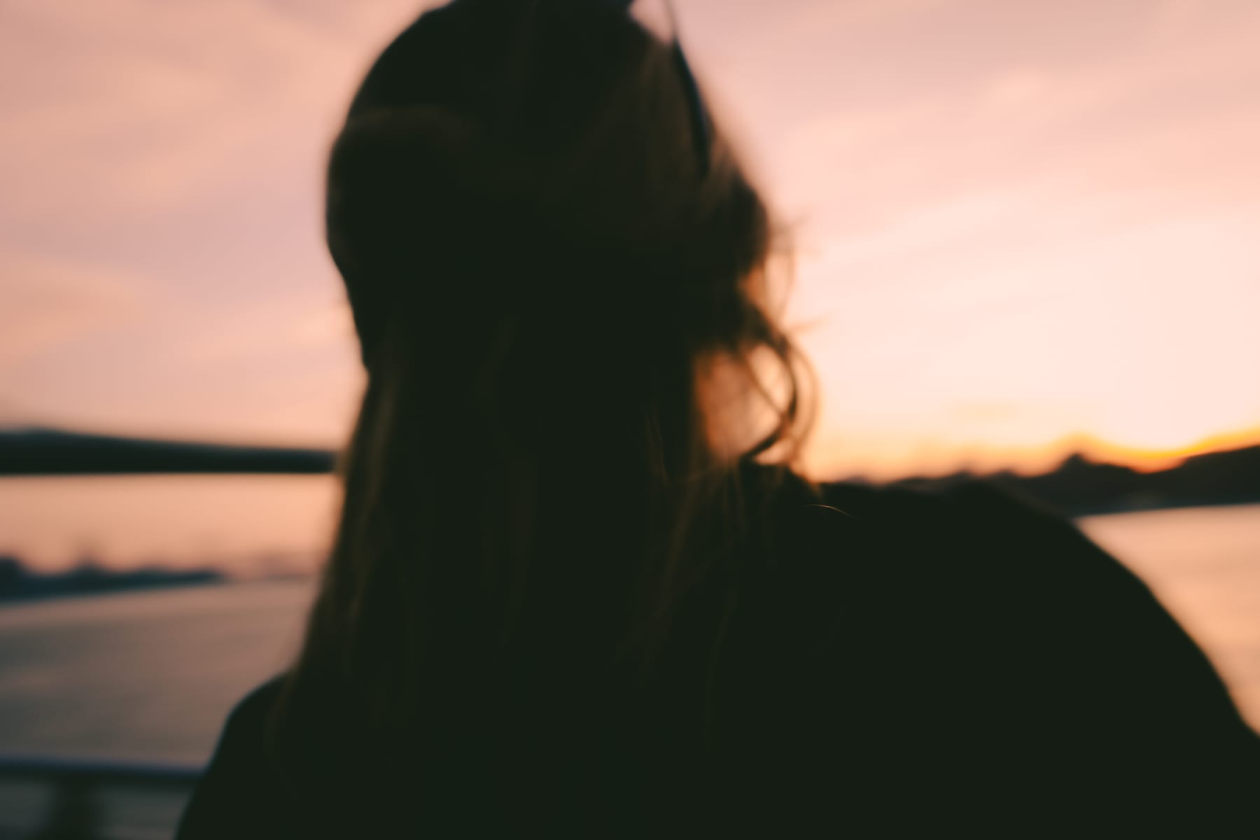 Silhouette of a long-haired figure by the river at sunset. (dummycopy)